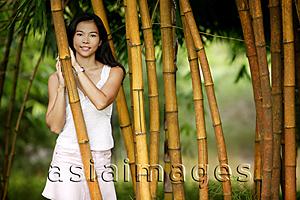 Asia Images Group - Young woman standing in a bamboo grove, smiling