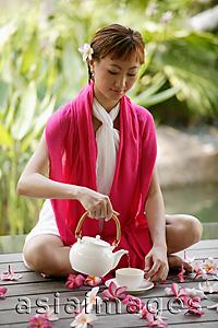 Asia Images Group - Young woman pouring tea, portrait