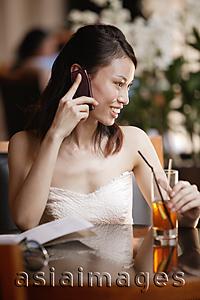 Asia Images Group - Young woman using mobile phone in a cafe