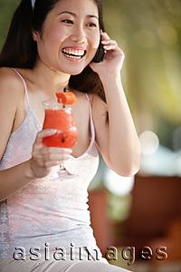 Asia Images Group - Young woman holding a drink and using mobile phone