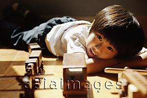 Asia Images Group - Young boy lying down with head in arms, looking at camera