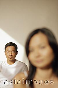 Asia Images Group - Young man looking at camera, woman in front of him