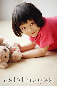 Asia Images Group - Young girl lying on front, holding teddy bear