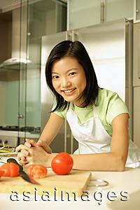 Asia Images Group - Young woman leaning on kitchen counter, hands clasped, looking at camera