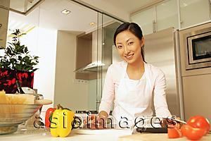 Asia Images Group - Young woman standing at kitchen counter, looking at camera.