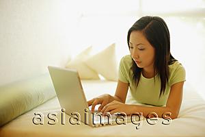 Asia Images Group - Young woman lying on bed, using laptop