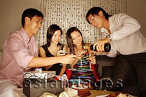 Asia Images Group - Couples sitting down with wine glasses, man pouring wine.