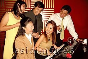 Asia Images Group - Woman playing the piano, friends around her