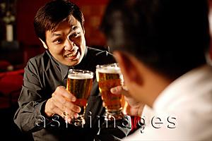 Asia Images Group - Two men toasting with beer glasses, over the shoulder view