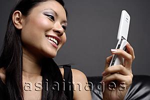 Asia Images Group -  Young woman looking at mobile phone, smiling