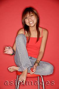 Asia Images Group - Young woman on stool holding nail polish bottle