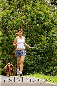 Asia Images Group - Young woman jogging with her dog