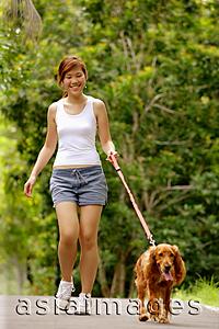 Asia Images Group - Young woman walking with her dog