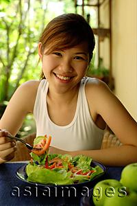 Asia Images Group - Woman eating salad, looking at camera