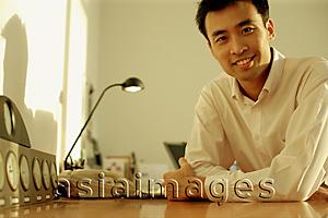Asia Images Group - Executive sitting at desk, arms crossed
