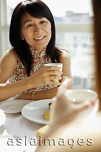 Asia Images Group - Woman holding teacup facing another woman