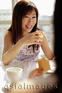Asia Images Group - Woman holding cake slice, facing another woman