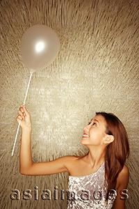 Asia Images Group - Young woman holding balloon, looking up