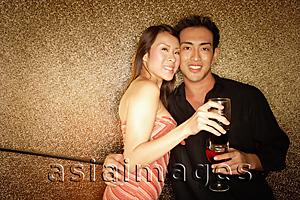 Asia Images Group - Couple standing with wine glass, looking at camera