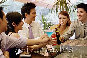 Asia Images Group - Young adults at bar counter toasting with drinks