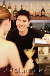 Asia Images Group - Man holding cocktail mixer, pouring drink for woman