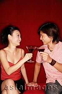 Asia Images Group - Couple sitting side by side, toasting with drinks