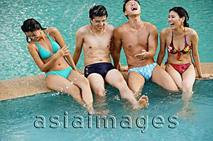 Asia Images Group - Couples at edge of swimming pool, sitting side by side laughing