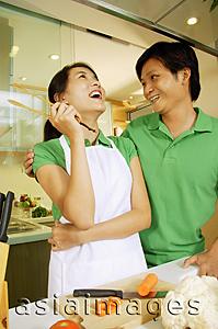 Asia Images Group - Couple in kitchen, man with arm around woman