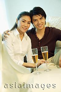 Asia Images Group - Couple looking at camera, champagne glasses in front of them