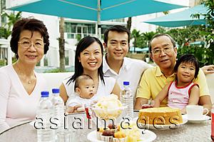 Asia Images Group - Three generation family sitting around table, looking at camera