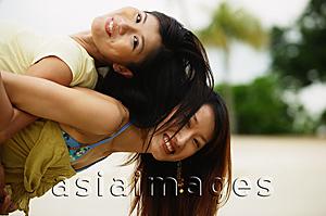 Asia Images Group - Young woman carrying friend on back, looking at camera