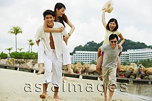 Asia Images Group - Couples on beach, men carrying women on their backs