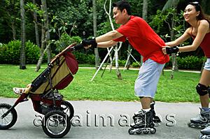 Asia Images Group - Father skating and pushing stroller, mother holding on to waist