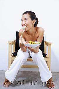 Asia Images Group - Woman sitting on chair, holding bowl of salad, smiling at camera