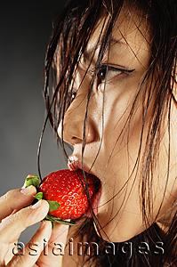 Asia Images Group - Young woman with wet hair, eating a strawberry