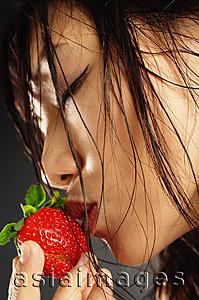 Asia Images Group - Young woman with wet hair, kissing a strawberry