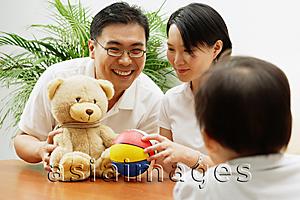 Asia Images Group - Father and mother with stuffed toy and ball, daughter looking at them, rearview