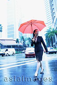 Asia Images Group - Business woman with umbrella, crossing the road