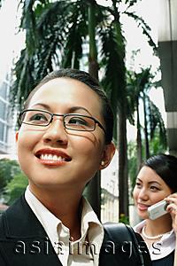 Asia Images Group - Business woman, smiling, looking away, woman in the background on the phone