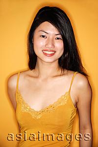 Asia Images Group - Young woman in yellow tank top standing against yellow wall
