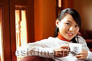 Asia Images Group - Young woman holding cup, looking at camera