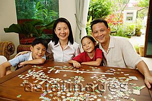 Asia Images Group -  Family in living room, jigsaw puzzle on table, portrait