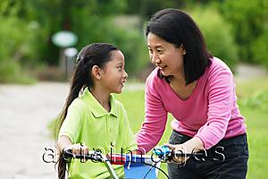 Asia Images Group - Young girl on bicycle, mother next to her, face to face