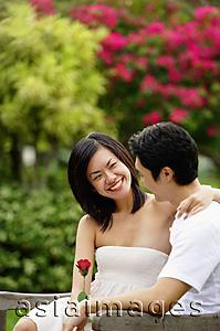 Asia Images Group - Couple sitting on park bench, looking at each other