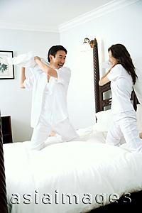 Asia Images Group - Couple in bedroom, having pillow fight