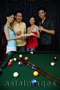 Asia Images Group - Couples smiling at camera, holding plate of appetizers between them
