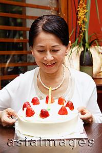 Asia Images Group - Mature woman looking at birthday cake, smiling