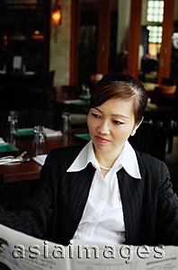 Asia Images Group - Businesswoman in restaurant, reading newspaper
