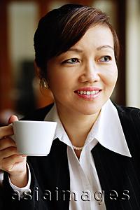 Asia Images Group - Businesswoman holding cup, looking away