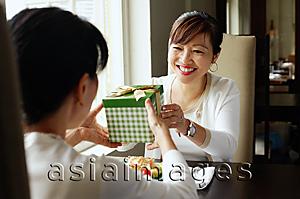 Asia Images Group - Woman giving gift to person sitting opposite her